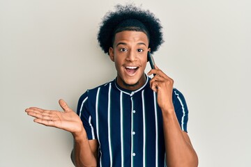 African american man with afro hair having conversation talking on the smartphone celebrating achievement with happy smile and winner expression with raised hand