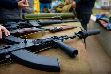 Automatic rifle with a silencer on the table with weapons.
