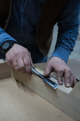 a man planes a wooden board with a special tool