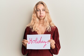 Young blonde girl holding holidays banner message depressed and worry for distress, crying angry and afraid. sad expression.