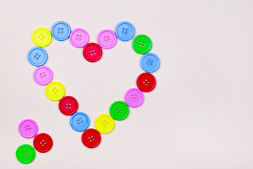 Heart shaped frame of colorful multicolor round painted wooden handmade sewing buttons isolated, close up, elevated top view