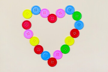 Heart shaped frame of colorful multicolor round painted wooden handmade sewing buttons isolated, close up, elevated top view