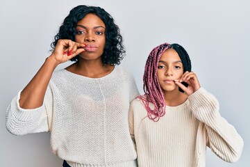 Beautiful african american mother and daughter wearing casual clothes and hugging mouth and lips...