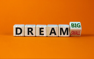 Dream small or big symbol. Turned wooden cubes and changed words 'dream small' to 'dream big'. Beautiful orange background, copy space. Business and dream small or big concept.