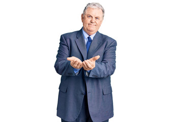 Senior grey-haired man wearing business jacket smiling with hands palms together receiving or giving gesture. hold and protection