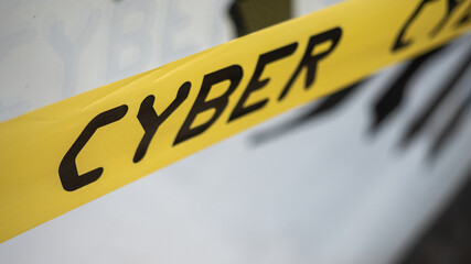 Gelbes Absperrband mit schwarzer Aufschrift Cyber als Symbol für Cyberkriminalität