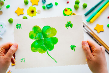 Drawing a green lucky clover st. Patrick. Top view of the hands.  Saint Patrick's Day concept.