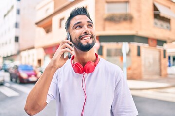 Young arab man smiling happy talking on the smartphone and using headphones at the city.