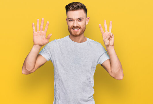 Young redhead man wearing casual grey t shirt showing and pointing up with fingers number eight while smiling confident and happy.