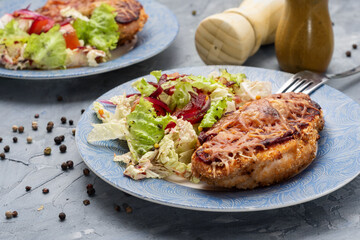 Chicken baked with cheese on a blue plate. Chicken fillet with salad on a plate.