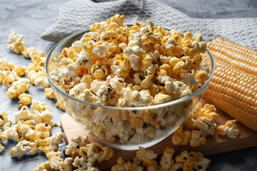 Sweet popcorn in a deep glass cup on a wooden board.