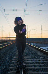 White Caucasian woman with a purple ribbon in her hair walking on the train tracks, concept of balance and vitality.