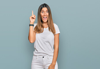 Young woman wearing casual white t shirt pointing finger up with successful idea. exited and happy. number one.
