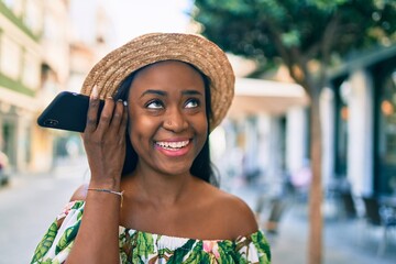 Young african american tourist woman on vacation smiling happy listening audio message using smartphone at the city.