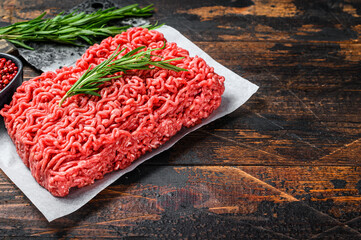 Raw forcemeat beef, ground meat on butcher paper. Dark wooden background. Top view. Copy space