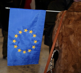 european union flag hold by woman in winter coat, evening street 