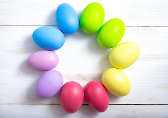 Bright colorful Easter eggs in the form of a wreath on a light wooden background. Easter concept.