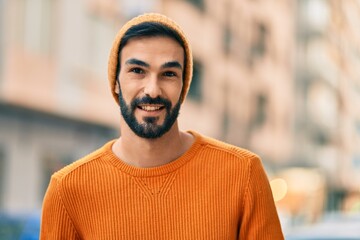 Fototapeta premium Young hispanic man wearing winter style smiling happy at the city.