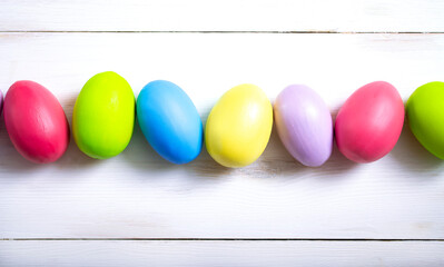 Bright Easter eggs are laid out in a row on a white wooden background. Easter background.