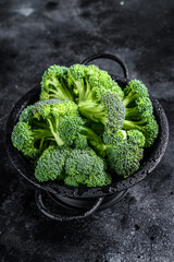 Organic Raw green broccoli cabbage  in a colander. Black background. Top view