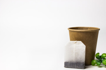 dry tea bag near craft glass with green leaves on white background