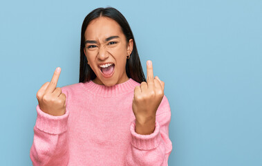 Young asian woman wearing casual winter sweater showing middle finger doing fuck you bad expression, provocation and rude attitude. screaming excited