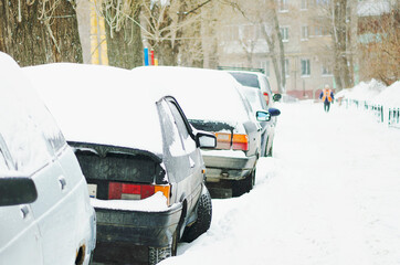 Cars parked in a residential yard on a winter day. Frost, a lot of snow. Winter in Russia.