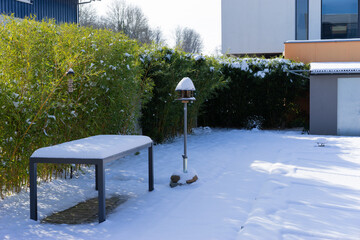 Table and bird feeder covered with snow in garden.