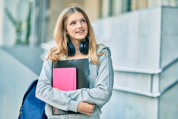 Beautiful caucasian student teenager smiling happy using headphones at the city.