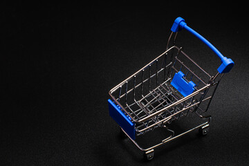 Small blue shopping cart on a black background. Copspace