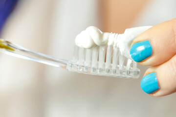 Toothbrush with paste on top in female hands.