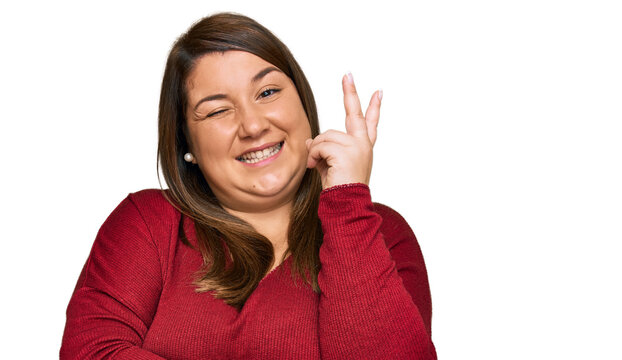 Beautiful brunette plus size woman wearing casual clothes smiling with happy face winking at the camera doing victory sign. number two.