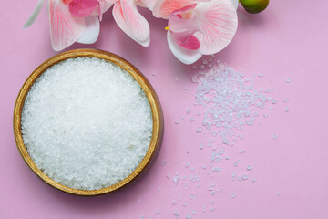 Bath salt in a wooden bowl and with orchid flowers close-up, with blurred soft focus on a pink background, spa concept, baths, massage and relaxation, scrub and body care