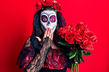Young woman wearing day of the dead costume holding flowers covering mouth with hand, shocked and afraid for mistake. surprised expression