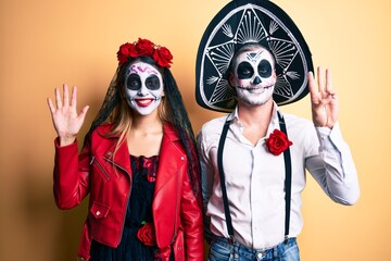Fototapeta na wymiar Couple wearing day of the dead costume over yellow showing and pointing up with fingers number eight while smiling confident and happy.