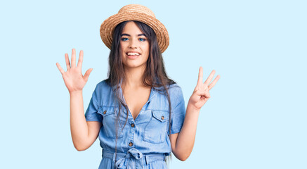 Obraz na płótnie Canvas Brunette teenager girl wearing summer hat showing and pointing up with fingers number eight while smiling confident and happy.