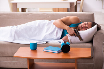 Young man lying on the sofa in time management concept
