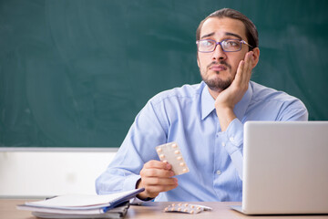 Young sick male teacher in the classroom