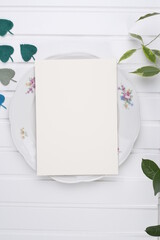 Kartka papieru na porcelanowym talerzu i listki na białym stole