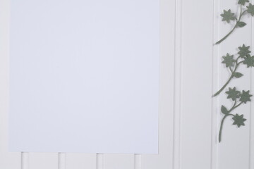 Kartka papieru biała na białym blacie drewnianym z listkami zielonymi