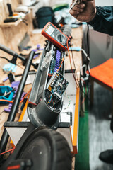 Man repairing electrical scooter in special workshop. Special workshop for repairing electrical scooters and bicycles.