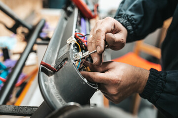 Man repairing electrical scooter in special workshop. Special workshop for repairing electrical scooters and bicycles.