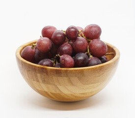 red grapes in a wooden bowl on a white background