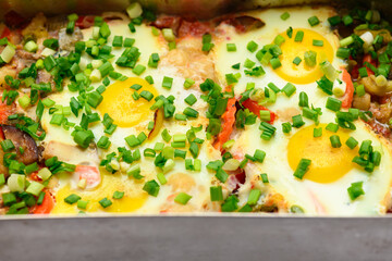 baked mixed vegetables and eggs close view, baking tray with tomatoes, broccoli and spices, home cooking