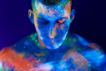 Portrait of a male bodybuilder. Man is painted in ultraviolet colors