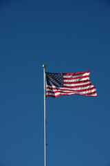 A United States flag waving high under a deep blue sky