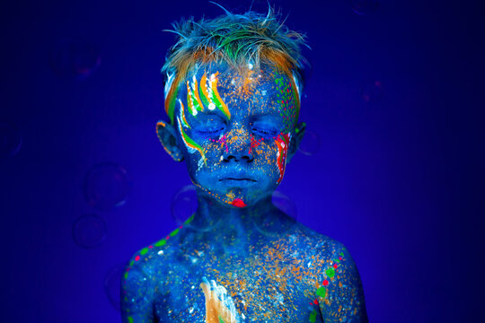 Portrait of a boy in UV light with soap bubbles