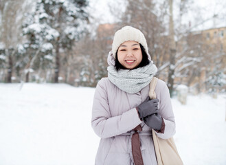 Fototapeta na wymiar Portrait of a positive fashionable Korean young woman on a walk in a winter snowy cold forest.