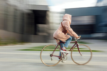 Naklejka premium Young woman in face medical mask riding bicycle roadway motion blur