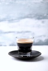 Coffee in glass cup on bright wooden background. 